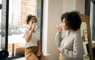 Mother and daughter drink water from a bottled water cooler at home