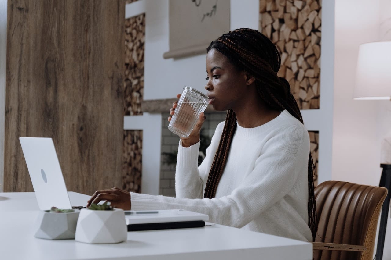 Woman works from home while enjoying water from a bottled water cooler