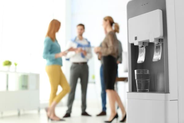 Colleagues socialise beside an office water cooler